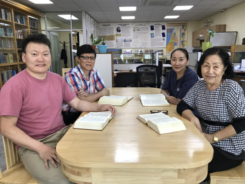 Das Team der mongolischen Bibelgesellschaft mit aufgeschlagenen hebräischen Bibeln.